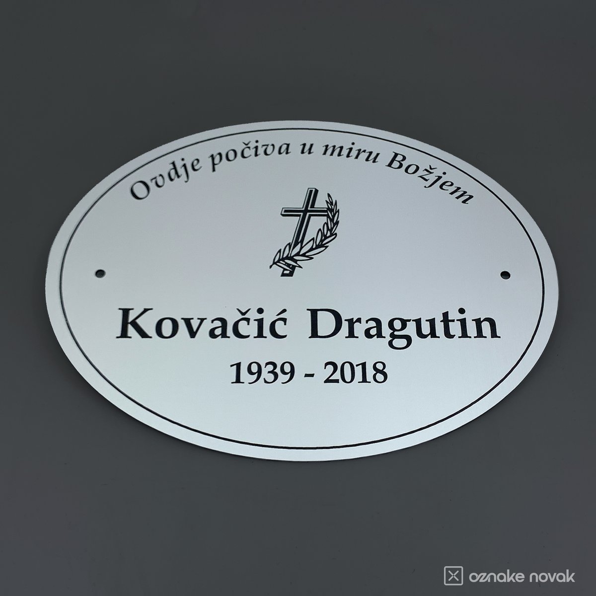 Smooth silver oval memorial plate with engraved name, years, a cross and arched dedication text