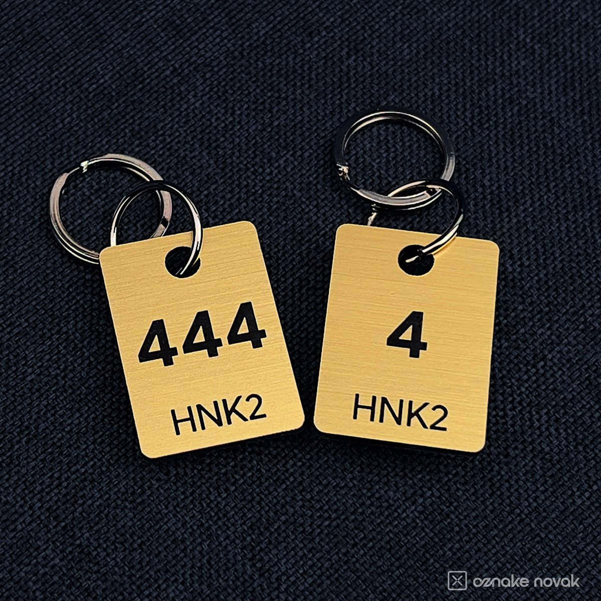 Brushed Gold cloakroom tags numbered 444 and 4 on dark fabric