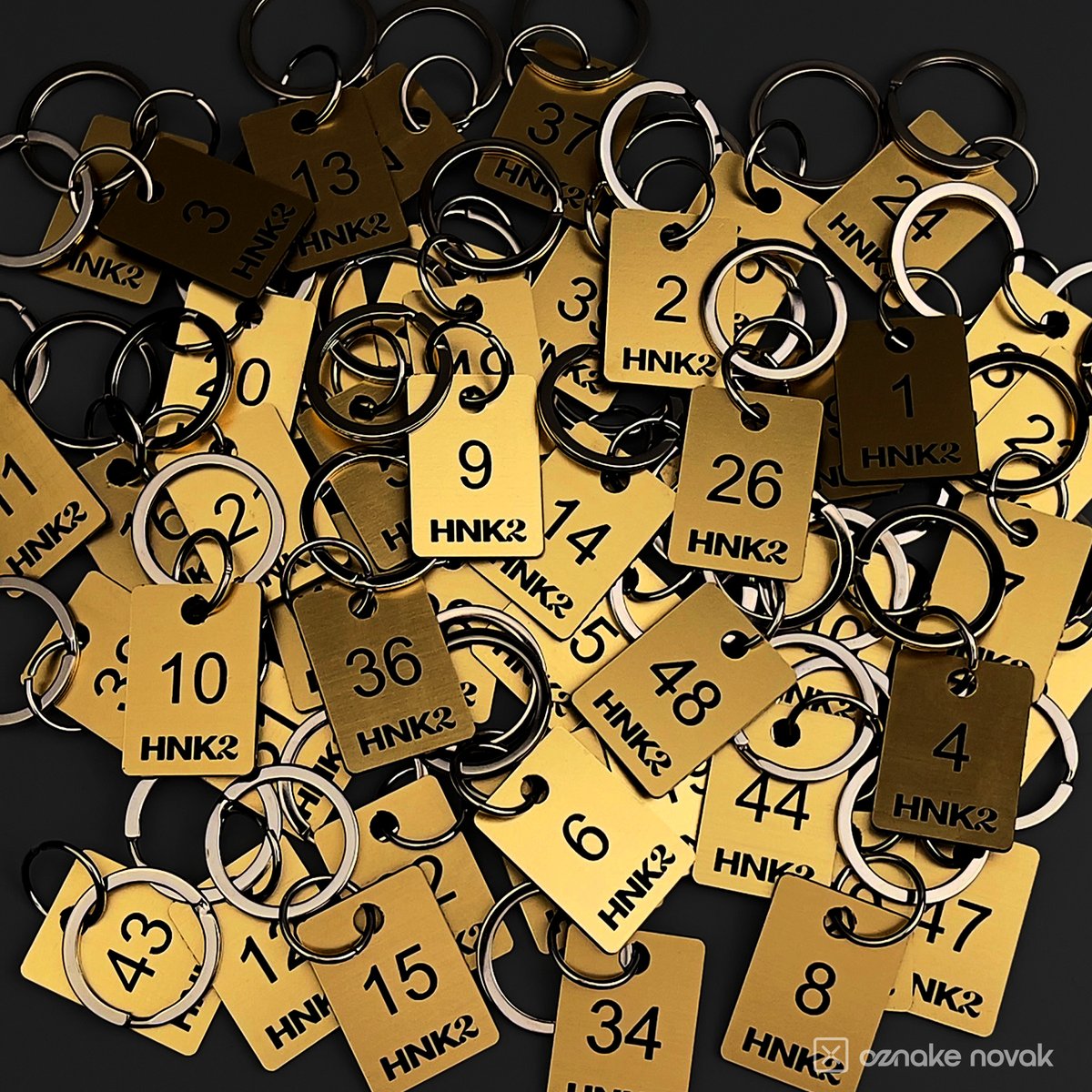 Pile of numbered gold cloakroom tags with HNK2 logo and metal rings
