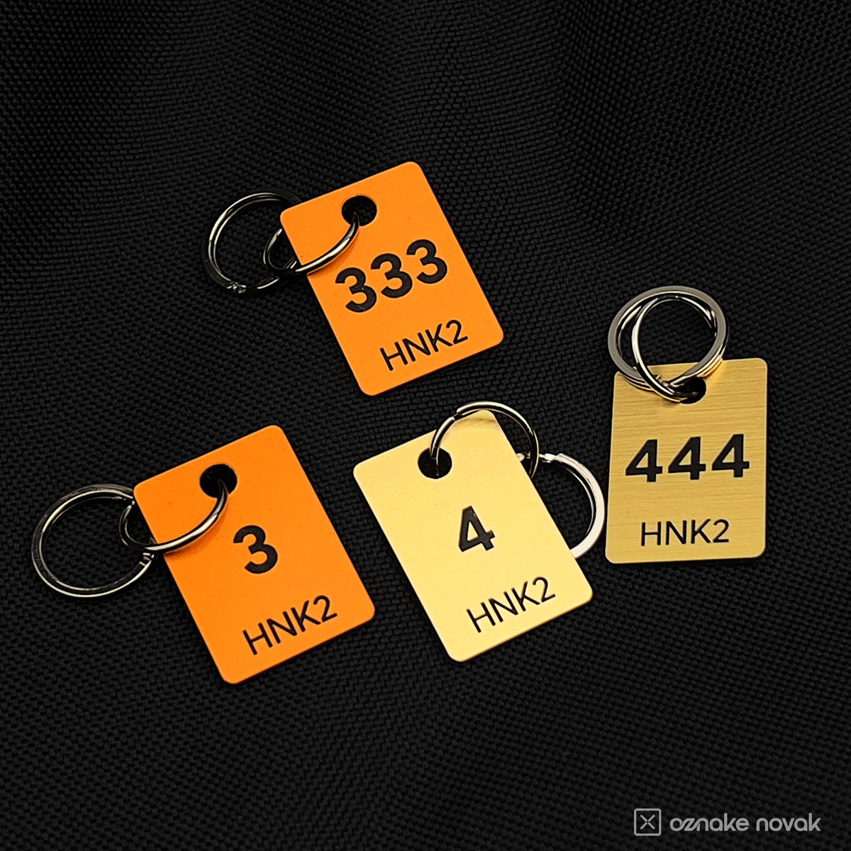 Cloakroom tag samples in Smooth Gold, European Gold and Brushed Gold on dark fabric