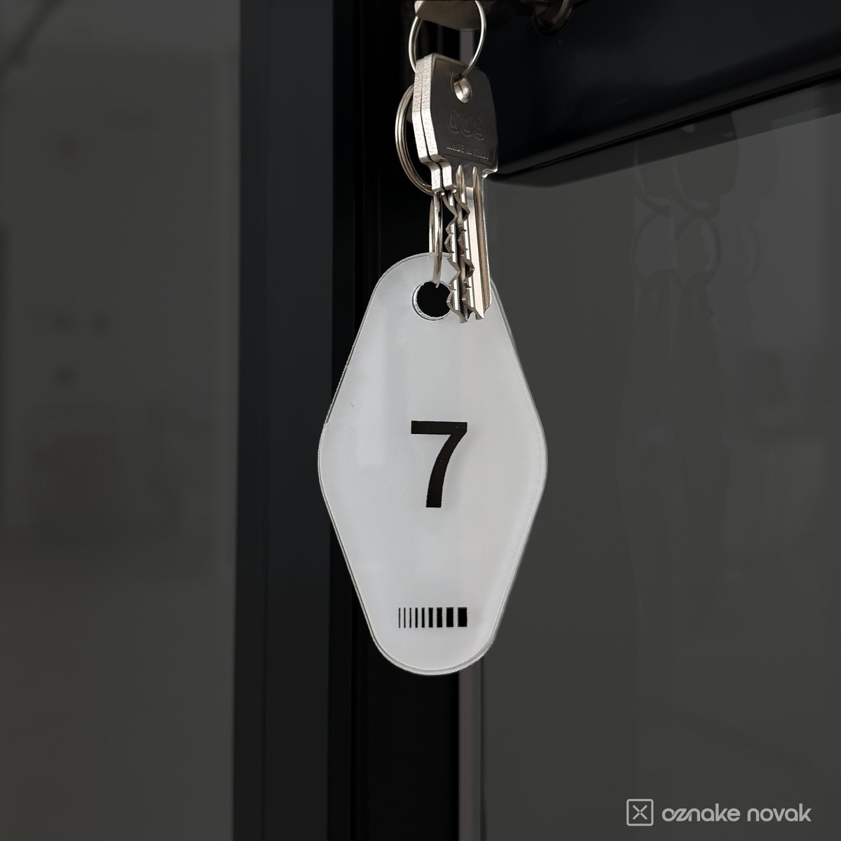 Opal white acrylic key tag number 7 hanging from keys in an office door lock