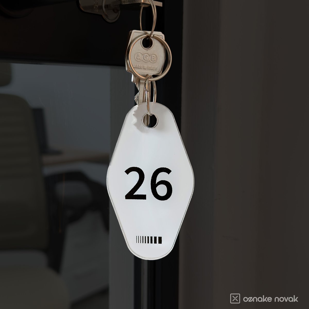 Opal white acrylic key tag number 26 on keys in an office door