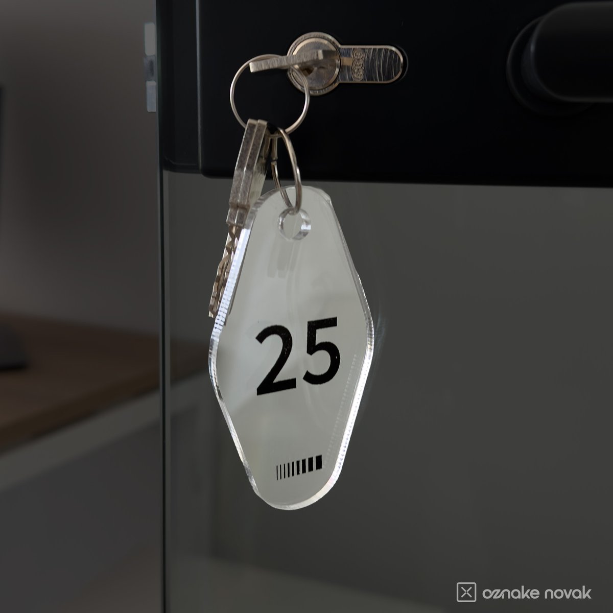 Clear acrylic key tag number 25 hanging from keys in a glass office door