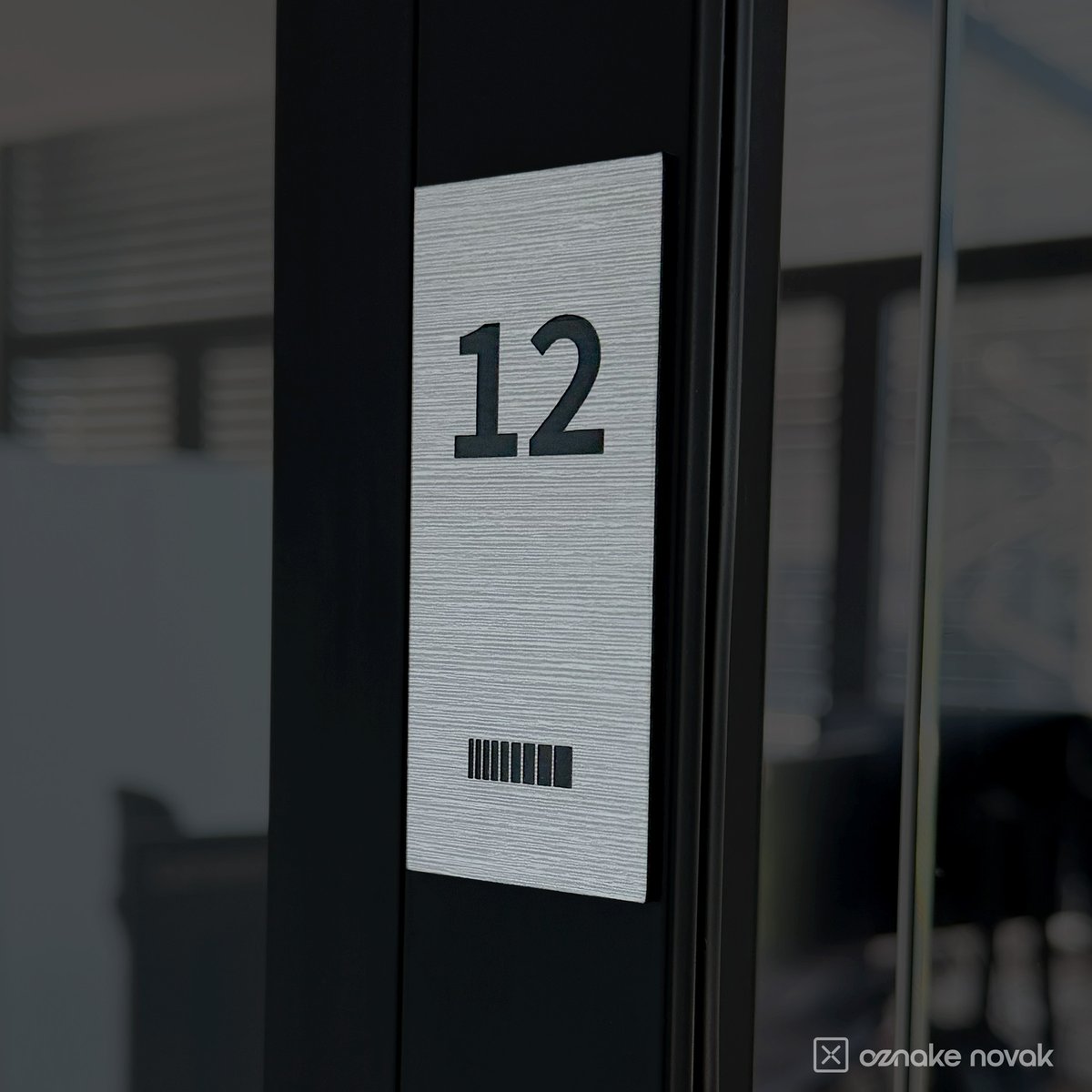 Brushed pewter office plate with engraved number 12 and Fina GS logo on a glass door frame