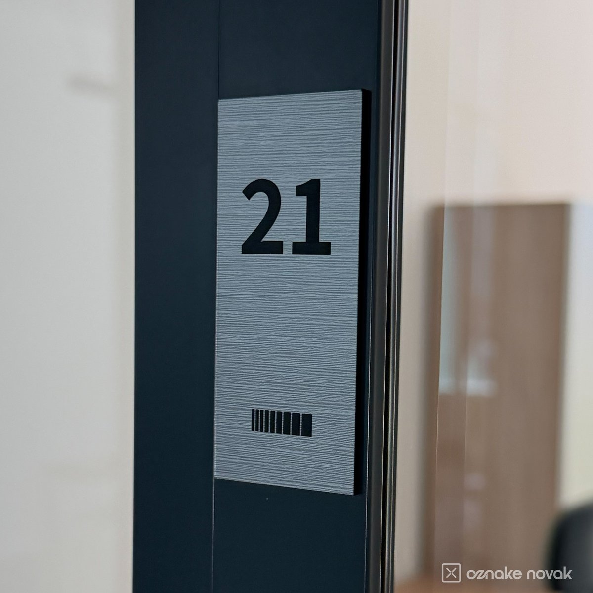 Brushed pewter office plate number 21 on a dark glass door frame