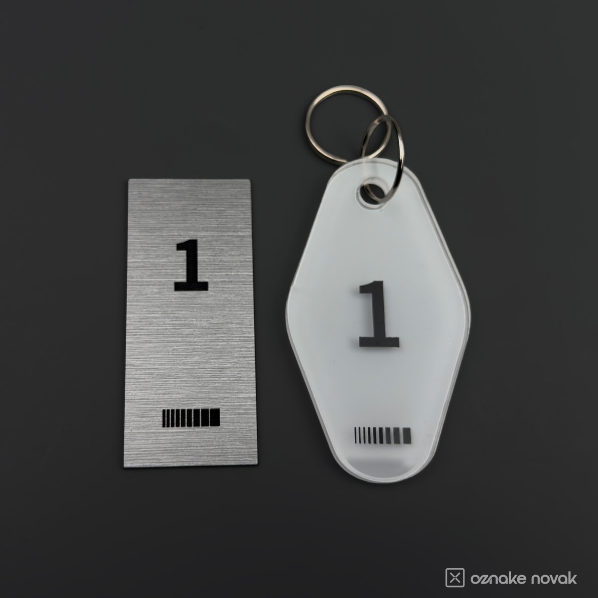 Brushed pewter plate and opal white key tag, both numbered 1, side by side