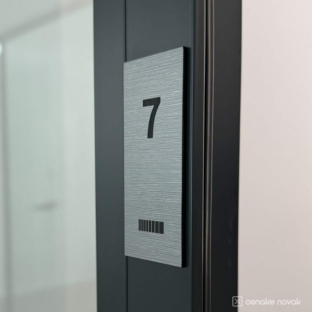 Brushed pewter office plate number 7 on an office door frame