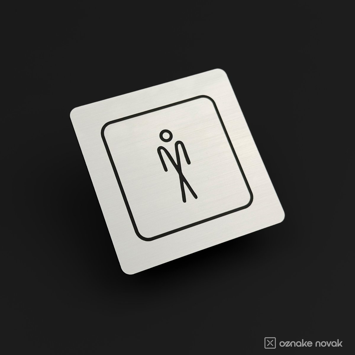 Brushed silver restroom sign with engraved men's pictogram on a dark background