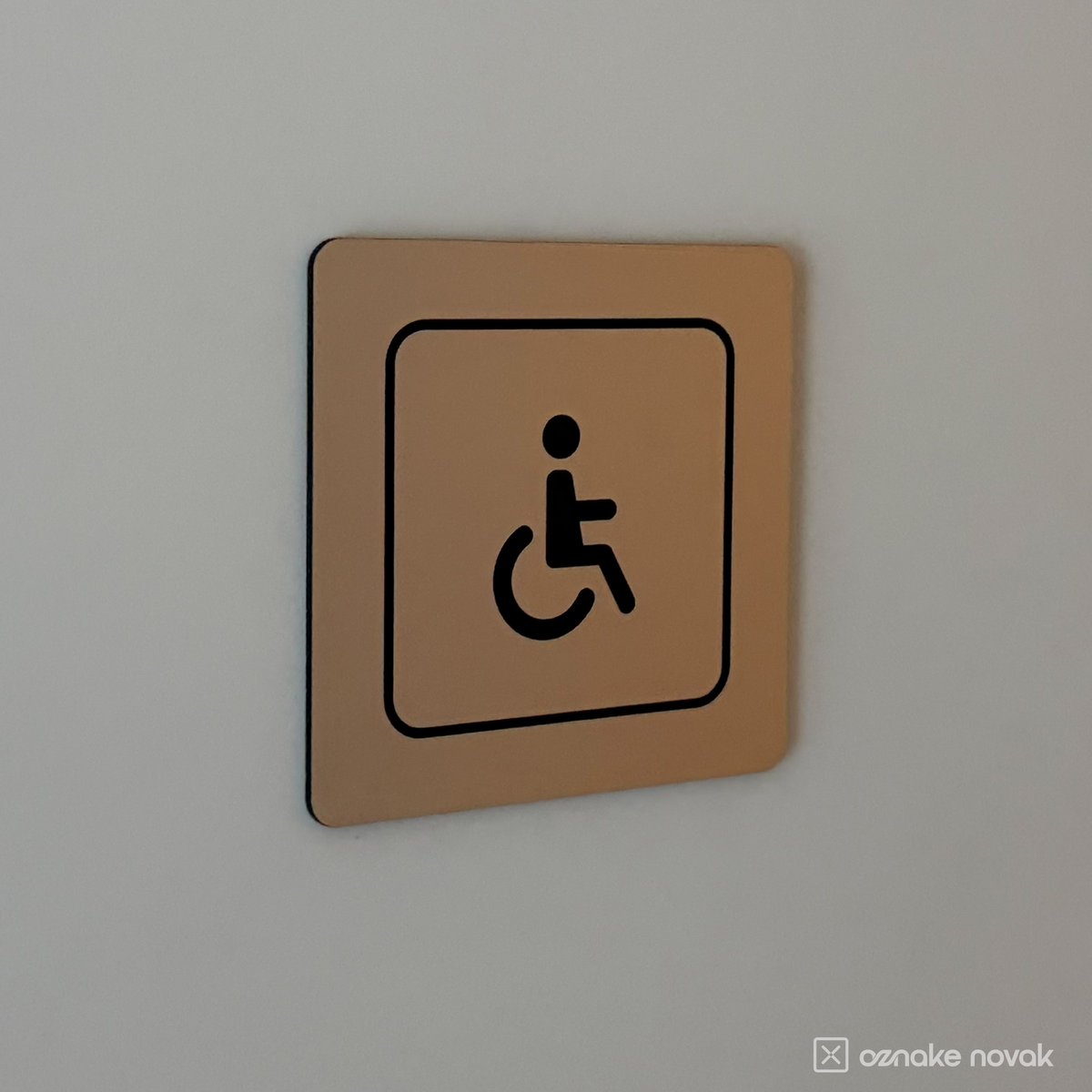 Accessible restroom sign mounted on a wall under warm light