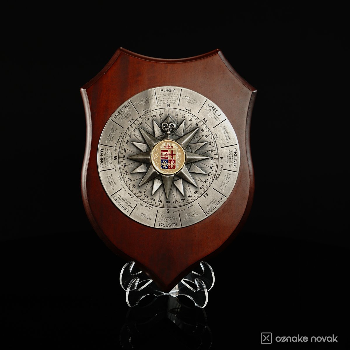 Front view of a wooden shield plaque with a silver compass rose emblem on a clear stand