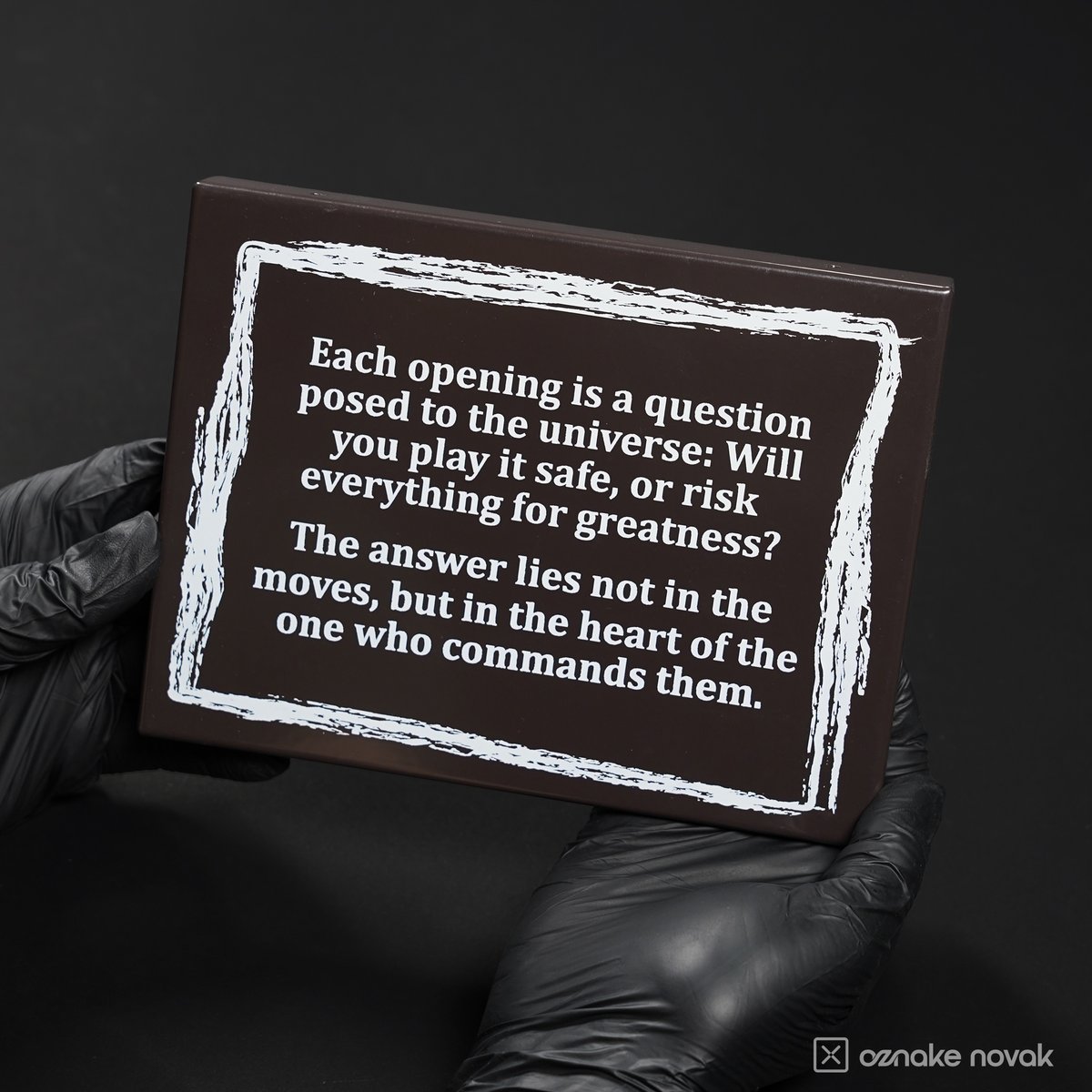 Gloved hands holding the dark brown chess quote name plate