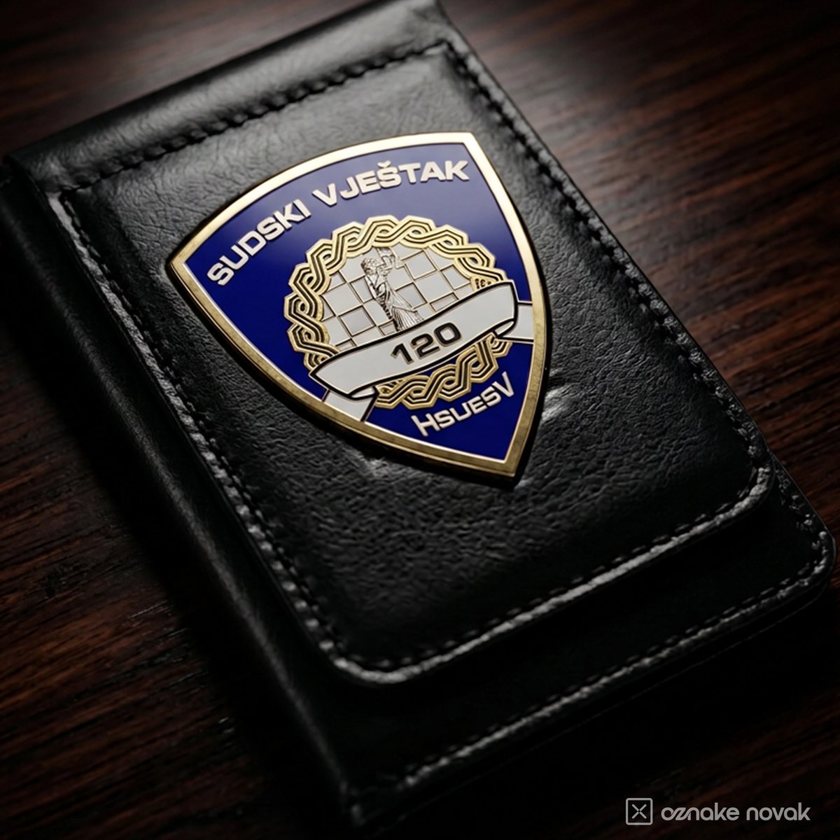 Close-up of an enamelled HSUESV court expert badge number 120 on a black leather case