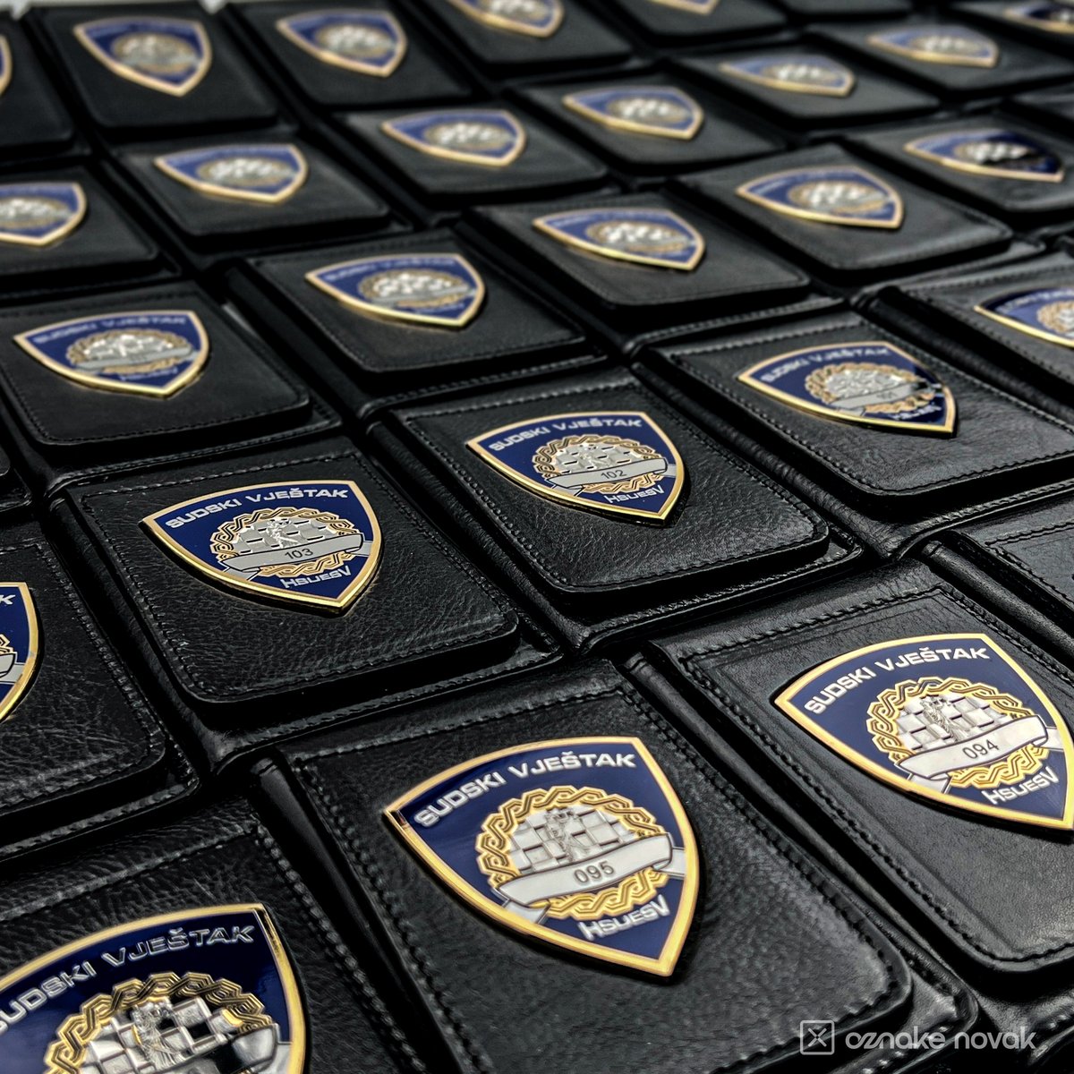 Series of black leather cases with numbered enamelled HSUESV badges laid out in rows